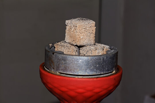 Smoldering coals of a hookah on a red bowl