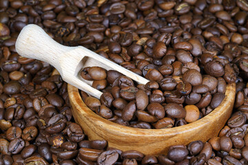 Coffee beans in a round wooden bowl close-up. Roasted aromatic coffee macro. Brown coffee background