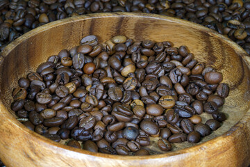 Coffee beans in a round wooden bowl close-up. Roasted aromatic coffee macro. Brown coffee background