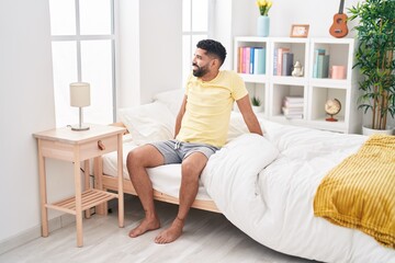 Young arab man smiling confident sitting on bed at bedroom