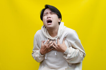 portrait of the anger expression of an Asian young man in beige hoodie, threatening, accusing, and looking for fight. A hysterical, mad depressed indonesian young man hand, shouts and screams loudly.
