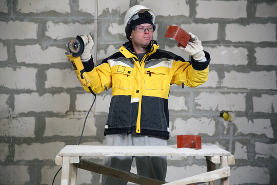 Locksmith in special clothes and goggles works in production. Worker. A man in a helmet and with a grinder in his hand. Industry. Builder. Metal processing with angle grinder