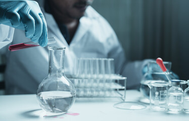 Scientist holding flask with lab glassware and chemistry laboratory test tubes Research and development in science laboratory, science technology concept
