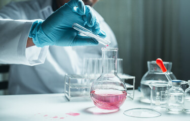 Scientist holding flask with lab glassware and chemistry laboratory test tubes Research and...