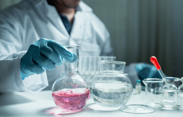 Scientist holding flask with lab glassware and chemistry laboratory test tubes Research and...