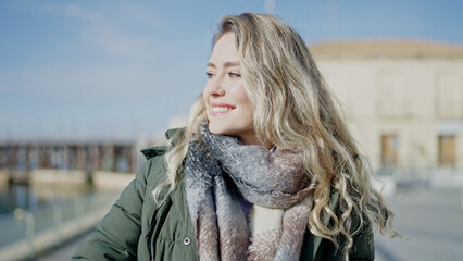 Young blonde woman smiling confident looking to the side at seaside