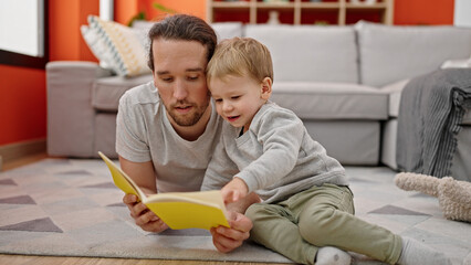 Father and son reading book sitting together on floor at home