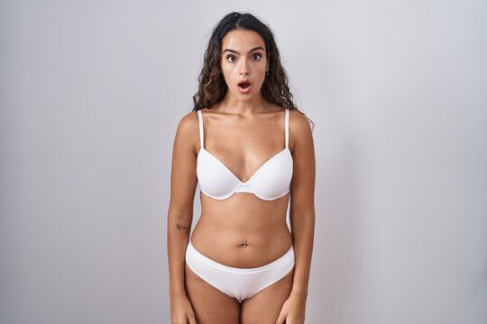 Young hispanic woman wearing white lingerie afraid and shocked with surprise and amazed expression, fear and excited face.