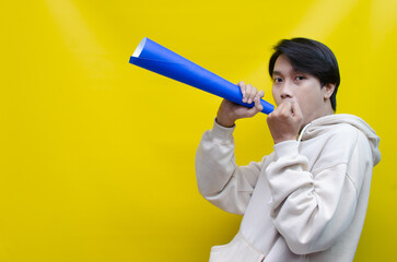 Fototapeta premium Euphoric and overjoyed asian man raising fist and holding paper megaphone giving announcement