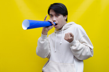 Euphoric and overjoyed asian man raising fist and holding paper megaphone giving announcement