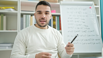 Fototapeta premium Young hispanic man teacher teaching maths lesson at library university