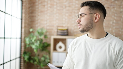 Young hispanic man business worker standing with relaxed expression at office