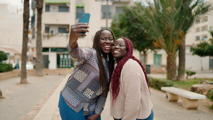 Two african american friends smiling confident making selfie by the smartphone at park