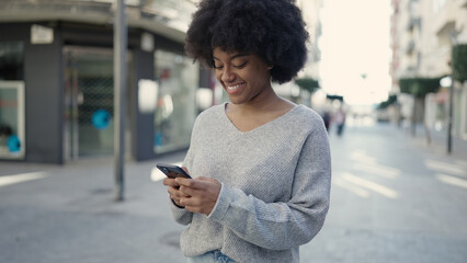 Fototapeta na wymiar African american woman smiling confident using smartphone at street