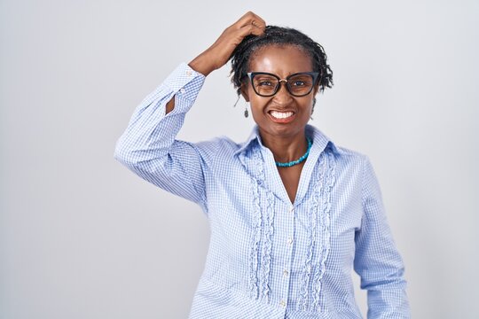 African woman with dreadlocks standing over white background wearing glasses confuse and wonder about question. uncertain with doubt, thinking with hand on head. pensive concept.