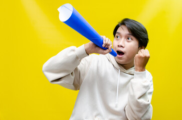 Euphoric and overjoyed asian man raising fist and holding paper megaphone giving announcement
