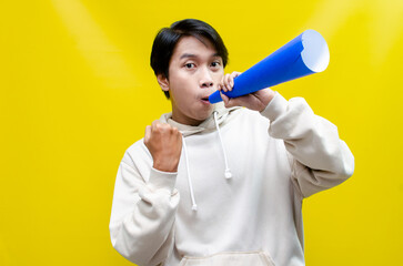 Euphoric and overjoyed asian man raising fist and holding paper megaphone giving announcement