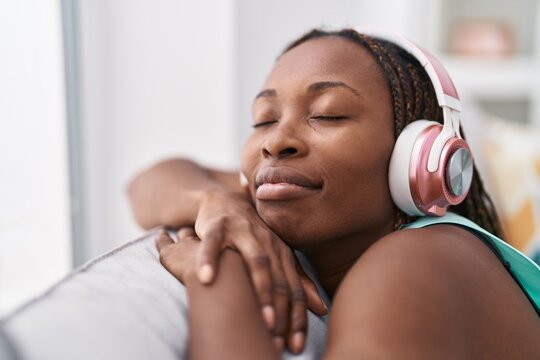 African american woman listening to music relaxed on sofa at home