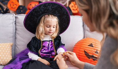 Adorable blonde girl sitting on sofa having halloween make up on hand at home