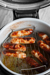 Pork sausages on a rack cooked in an air fryer. Healthy low cost cooking concept
