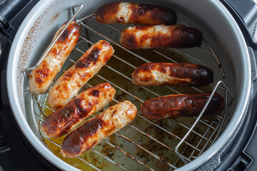 Pork sausages on a rack cooked in an air fryer. Healthy low cost cooking concept