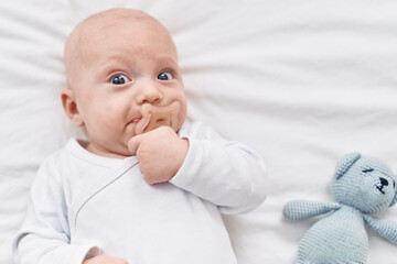 Adorable caucasian baby lying on bed sucking pacifier at bedroom