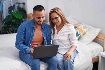 Man and woman mother and son using laptop at bedroom