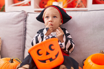 Adorable caucasian boy wearing pirate costume eating sweet at home