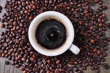  One cup of espresso and coffee beans on wooden surface