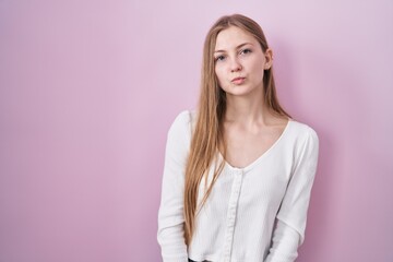 Fototapeta premium Young caucasian woman standing over pink background looking at the camera blowing a kiss on air being lovely and sexy. love expression.