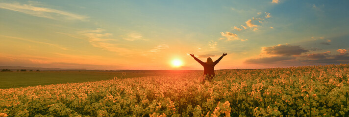 Happy woman on a flower field at sunrise  - 599936683