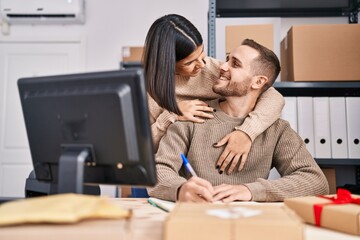 Man and woman ecommerce business workers hugging each other write on notebook at office