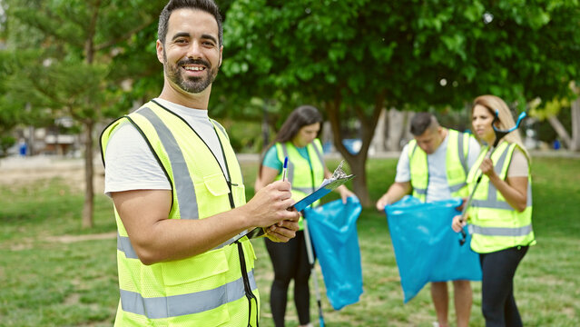 Group of people volunteers writing on clipboard smiling confident at park