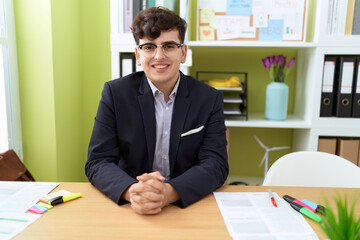 Non binary man business worker smiling confident sitting on table at office