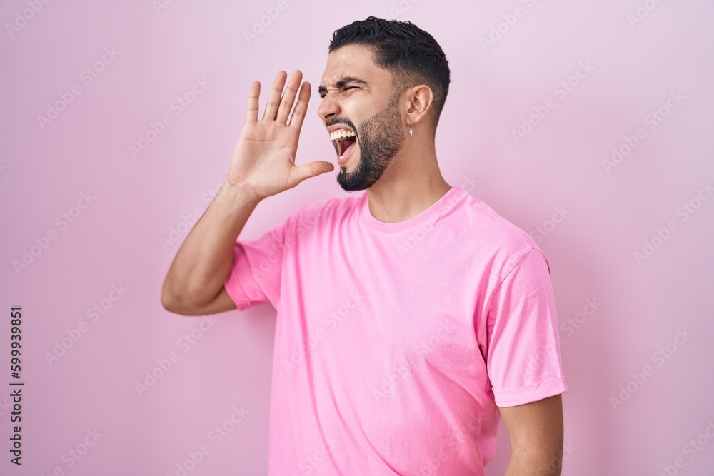 Canvas Prints Hispanic young man standing over pink background shouting and screaming loud to side with hand on mouth. communication concept.