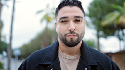Young arab man standing with serious expression at street