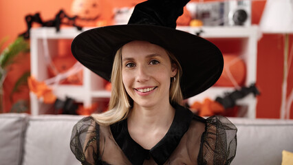 Young blonde woman wearing witch costume having halloween party at home