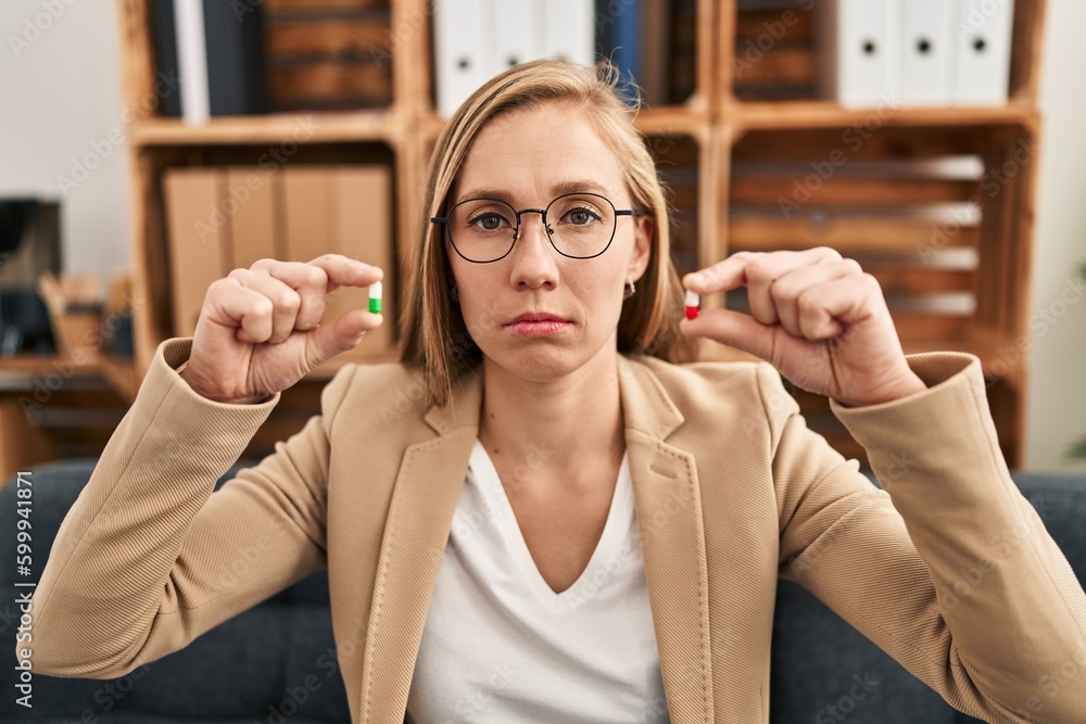 Poster young blonde woman holding pills at therapy depressed and worry for distress, crying angry and afrai