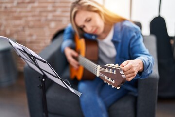 Fototapeta na wymiar Young blonde woman musician playing classical guitar at music studio