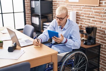 Young caucasian man business worker using touchpad writing on reminder paper at office
