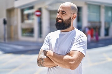 Young bald man standing with arms crossed gesture at street