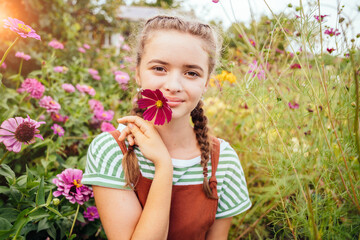 Portrait of adorable teenager girl with cute hairstyle wearing overalls taking care and enjoy...