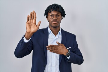 Young african man with dreadlocks wearing business jacket over white background swearing with hand...