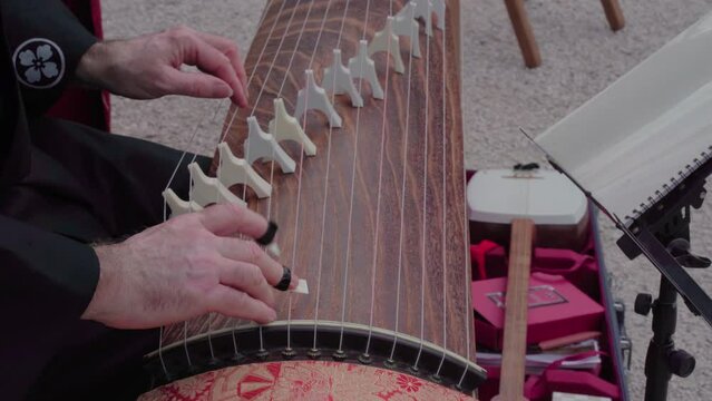 One man's hands play Japanese music with the koto
