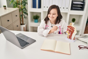 Down syndrome woman wearing doctor uniform pointing to anatomical model of respiratory system at clinic