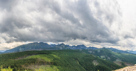 Panorama of the Polish High Tatras from the Kopieniec Wielki hill above the city of Zakopane on a cloudy summer day.