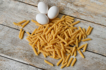Uncooked Italian pasta and chicken eggs. Heap of raw pasta.