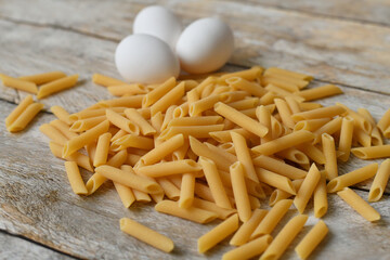 Uncooked Italian pasta and chicken eggs. Heap of raw pasta.