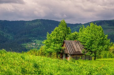 Fototapeta premium Mountain landscape in spring season. View of wooden hut on the glade among the trees, Beskids mountains, Poland.