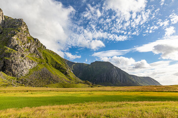 magical mountain massif that rises behind a pasture landscape in the blue cloudy sky,